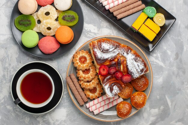 Vue de dessus petits gâteaux avec des biscuits tasse de thé et tarte sur blanc biscuit biscuit backgruond thé tarte au sucre sucré