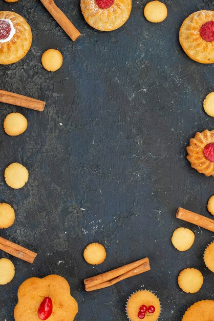 Vue de dessus petits gâteaux délicieux avec des biscuits à la crème à la cannelle sur le bureau sombre gâteau biscuit sucré dessert fruits