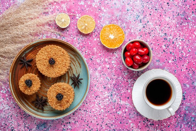 Vue de dessus de petits gâteaux délicieux avec cornouiller et thé sur la surface rose clair