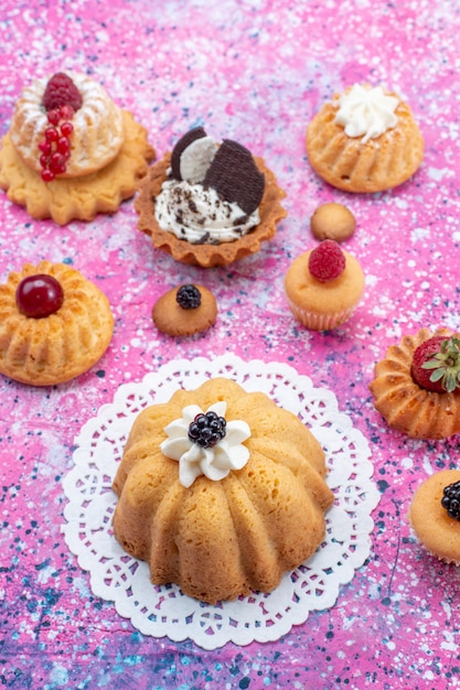 Photo gratuite vue de dessus de petits gâteaux délicieux avec de la crème avec différentes baies sur le gâteau de bureau lumineux léger biscuit berry sweet bake