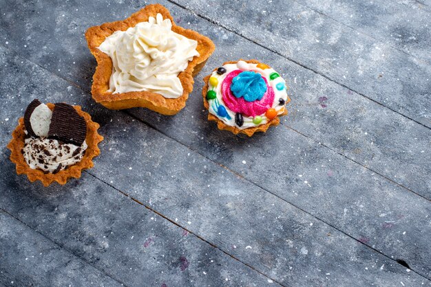 Vue de dessus petits gâteaux délicieux à la crème sur le fond clair bonbon gâteau sucré