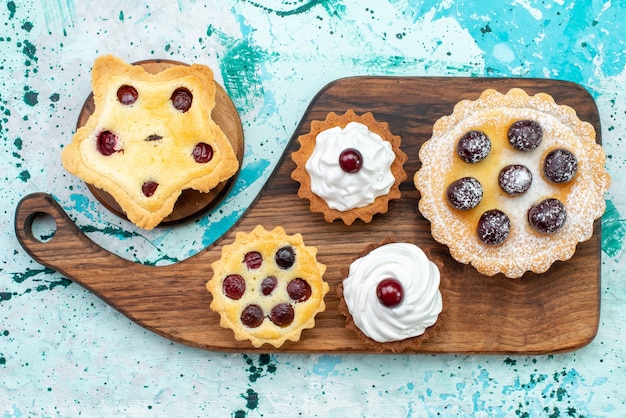 Vue de dessus petits gâteaux délicieux avec de la crème et des fruits sur une table légère gâteau biscuit crème de thé sucré