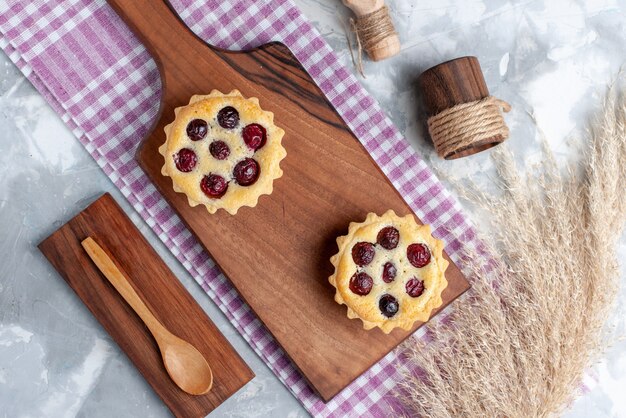 Vue de dessus petits gâteaux avec du sucre en poudre et des fruits sur une table légère crème gâteau aux fruits thé sucré