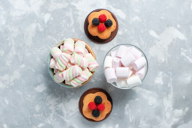 Vue de dessus de petits gâteaux avec des guimauves sur une surface blanche claire