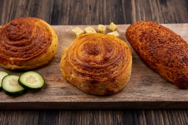 Photo gratuite vue de dessus des petits pains sur une planche de cuisine en bois avec des tranches de concombre et de fromage sur un fond en bois