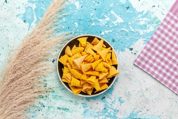 Vue de dessus peu de chips épicées à l'intérieur de la plaque sur fond bleu clair chips snack couleur croustillant calorie