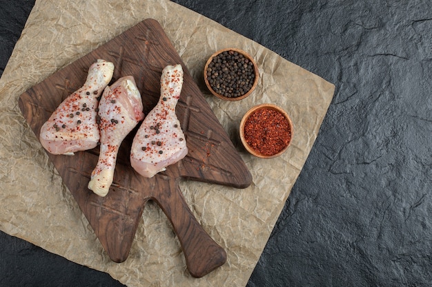 Vue De Dessus Pilon De Poulet Cru Et épices Sur Planche De Bois.