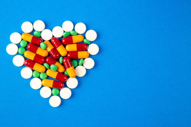Vue de dessus pilules en forme de coeur de couleur différente sur fond bleu