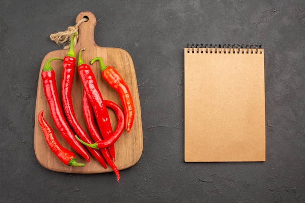 Vue de dessus des piments rouges sur une planche à découper et un ordinateur portable sur le tableau noir avec espace copie