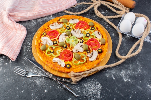 Vue de dessus pizza aux champignons avec tomates olives champignons avec oeufs sur le bureau gris pâte à pizza cuisine italienne