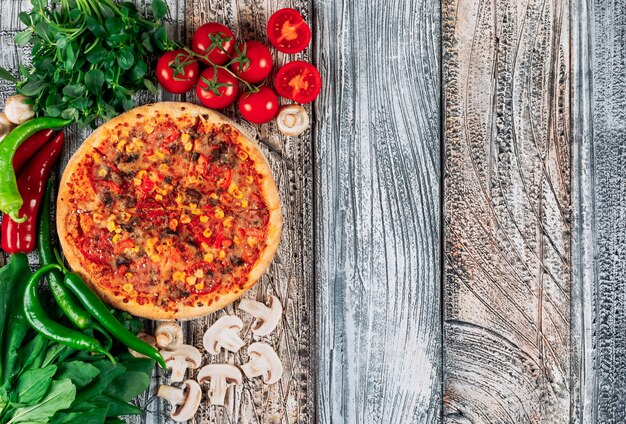 Vue de dessus pizza aux poivrons, champignons, tomates et grenerie sur fond de stuc clair. verticale