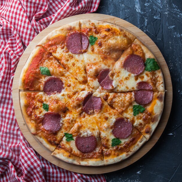 Vue de dessus pizza à la saucisse avec serviette en ustensiles de cuisine à bord