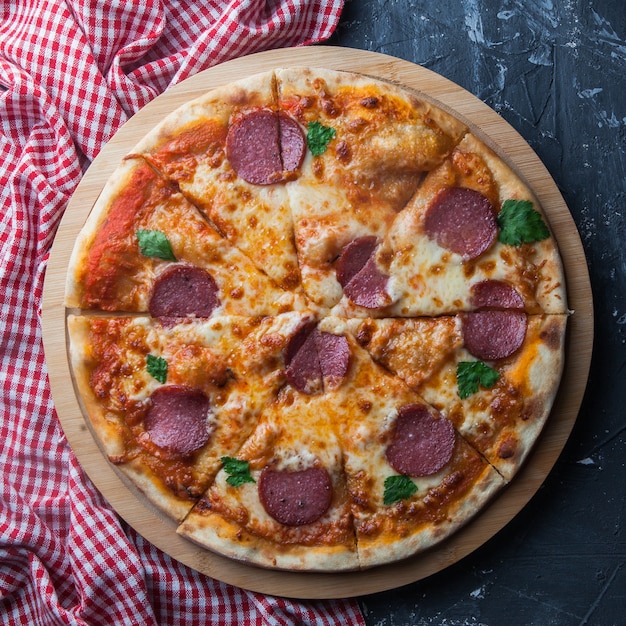 Vue de dessus pizza à la saucisse avec serviette en ustensiles de cuisine à bord