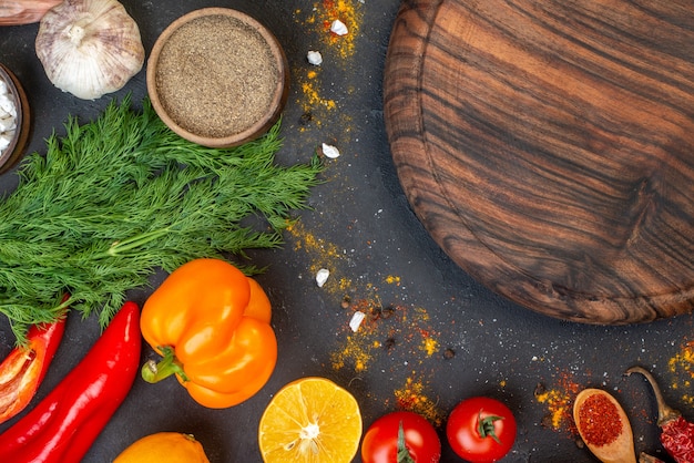 Vue de dessus planche de bois ronde poivrons ail tomates citron sur table