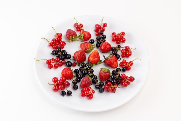 Vue de dessus de la plaque avec des fraises fraîches et moelleuses avec des myrtilles sur le fond blanc couleur de fruits frais moelleux