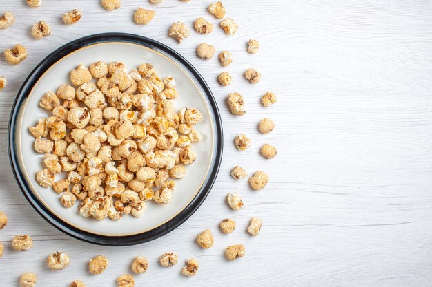 Vue de dessus de la plaque intérieure de pop-corn sucré sur surface blanche