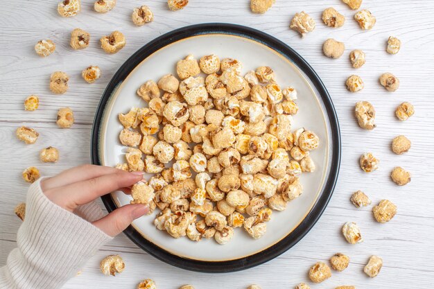 Vue de dessus de la plaque intérieure de pop-corn sucré sur surface blanche