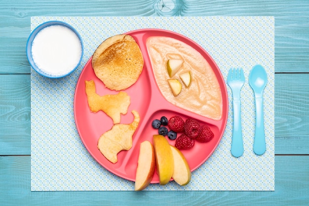 Vue de dessus de la plaque avec de la nourriture pour bébé et un assortiment de fruits