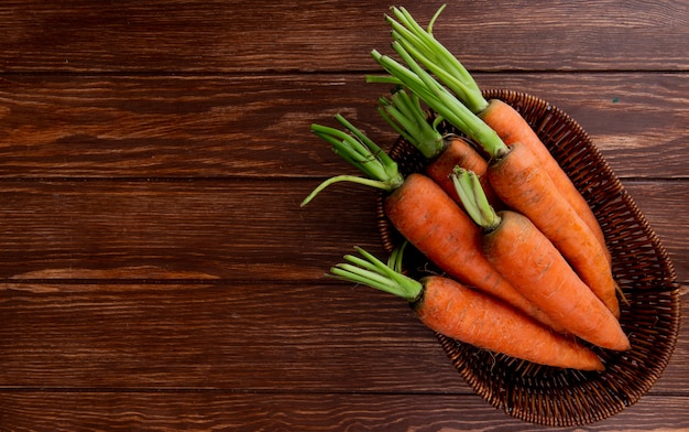 Vue de dessus de la plaque de panier avec des carottes sur fond en bois avec espace copie