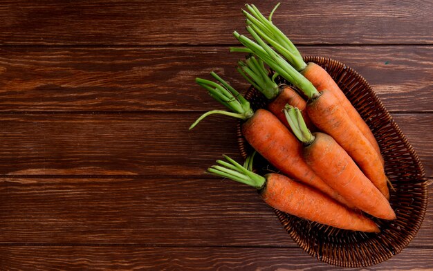 Vue de dessus de la plaque de panier avec des carottes sur fond en bois avec espace copie