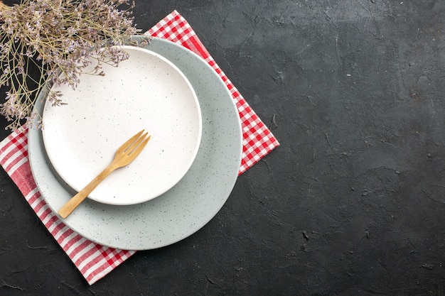 Photo gratuite vue de dessus plaque ronde blanche sur plaque grise sur une fourchette en bois serviette branche de fleurs séchées sur l'espace libre de table sombre