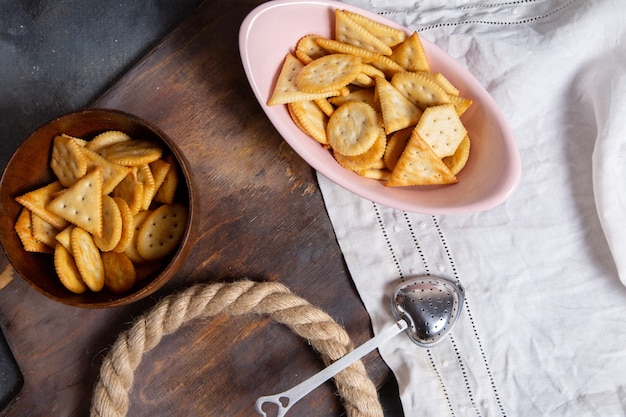 Vue de dessus plaque rose pleine de chips avec des cordes sur le fond gris craquelin croustillant snack couleur