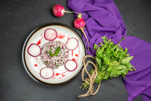 Vue de dessus un plat appétissant sauce radis sur l'assiette d'herbes à côté de la nappe violette