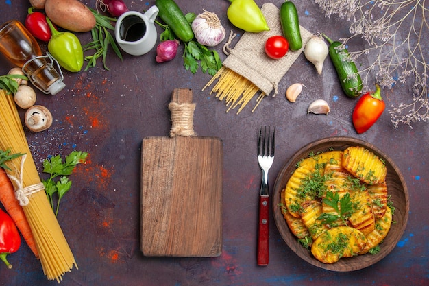 Vue de dessus un plat délicieux de pommes de terre cuites avec des légumes verts sur un plat de surface sombre