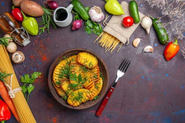 Vue de dessus un plat délicieux de pommes de terre cuites avec des légumes verts sur une surface sombre