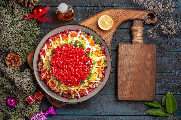 Vue de dessus Plat de Noël Plat de Noël sur la planche à côté de la planche de cuisine bouteille d'huile et de branches d'épinette avec des jouets d'arbre de Noël