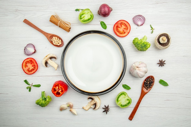 Photo gratuite vue de dessus plateau rond blanc cuillères en bois coupé tomates et autres trucs sur table grise