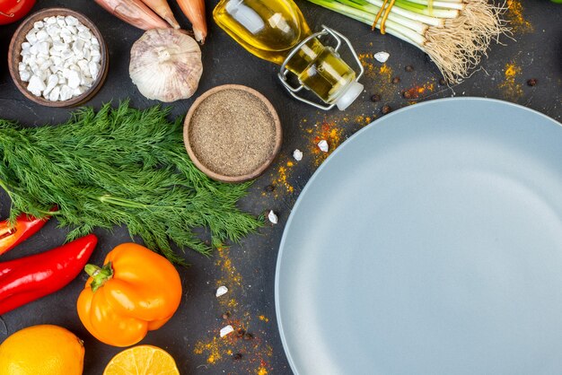 Vue de dessus plateau rond gris verts et épices sur table sombre