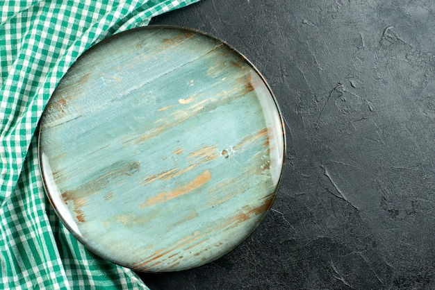 Vue de dessus plateau rond nappe verte et blanche sur l'espace libre de table noire