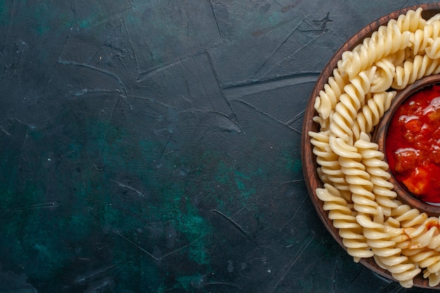 Vue de dessus de plus près en forme de pâtes italiennes avec sauce tomate sur surface bleu foncé