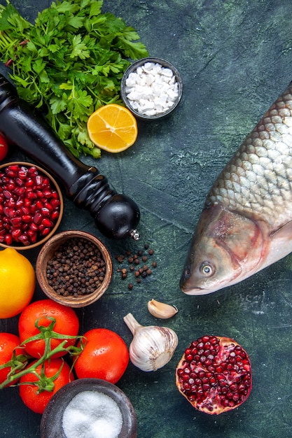 Photo gratuite vue de dessus poisson cru moulin à poivre tomates ail verts grenade sur table