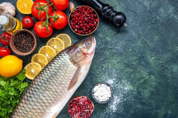 Vue de dessus poisson frais tomates moulin à poivre tranches de citron poivre noir sur table de cuisine