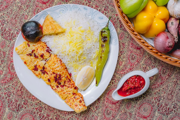 Vue de dessus poitrine de poulet grillée avec tomate de riz et poivron vert grillée avec une tranche de citron et sauce