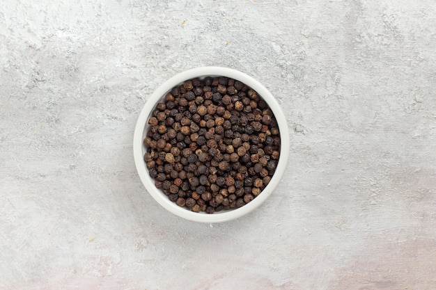 Vue de dessus poivre noir chaud et épicé à l'intérieur du pot sur la surface blanche épice piment produit ingrédient