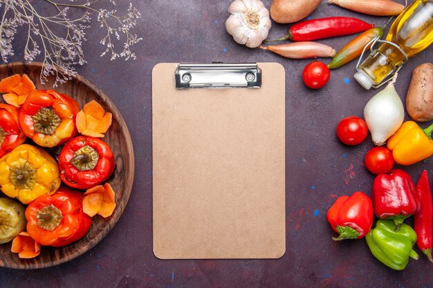 Vue de dessus poivrons cuits avec des légumes frais sur la surface sombre des légumes repas dolma food