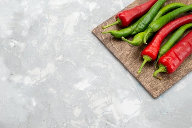 Vue de dessus poivrons épicés de couleur vert et rouge sur un bureau gris