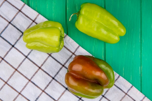 Vue de dessus des poivrons sur tissu à carreaux et surface verte