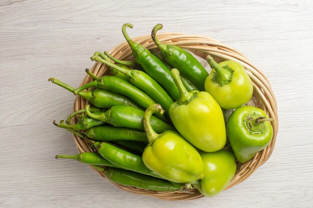 Vue de dessus des poivrons verts épicés avec des poivrons à l'intérieur du panier sur fond blanc