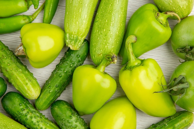 Photo gratuite vue de dessus des poivrons verts frais avec des concombres verts et des tomates sur un bureau blanc couleur repas de salade mûre chaud