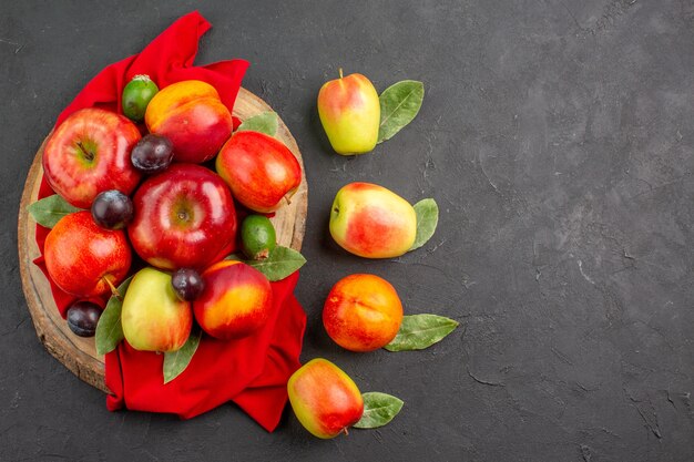 Vue de dessus des pommes fraîches avec des pêches et des prunes sur une table gris foncé, un arbre à jus mûr et moelleux