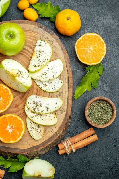 Vue de dessus des pommes et des mandarines coupées sur une planche de bois ronde