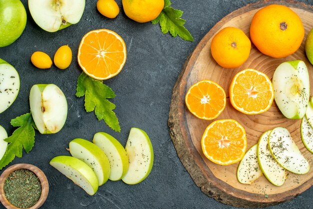 Vue de dessus des pommes et des mandarines coupées sur une planche de bois ronde