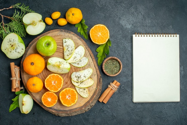 Vue de dessus des pommes et des mandarines coupées sur une planche de service rustique