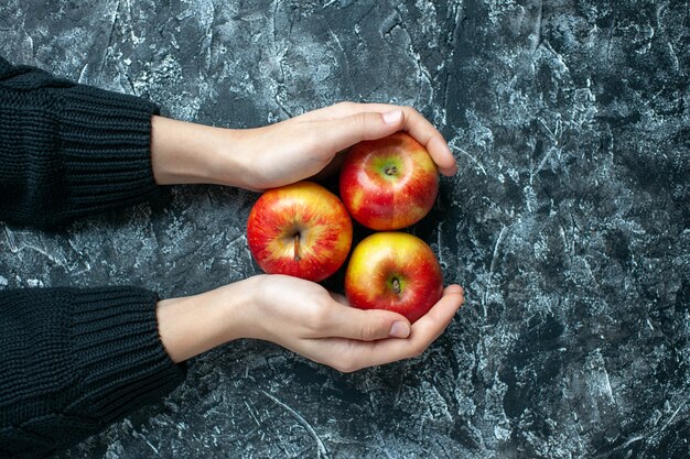 Vue de dessus des pommes mûres dans les mains des femmes sur fond gris avec lieu de copie