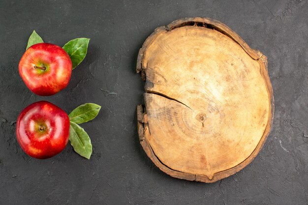 Vue de dessus pommes rouges fraîches fruits moelleux sur une table sombre fruits rouges frais mûrs