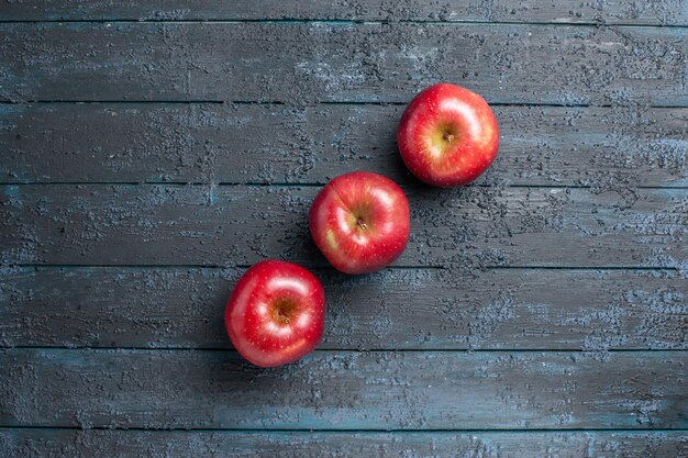 Vue de dessus pommes rouges fraîches fruits mûrs et moelleux bordés sur un bureau bleu foncé de nombreux fruits arbre de couleur rouge plante fraîche